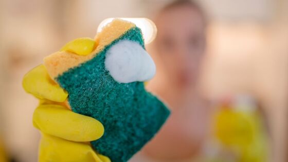 Close up vrouw met schoonmaakhandschoenen die spons vasthoudt Banner afbeelding